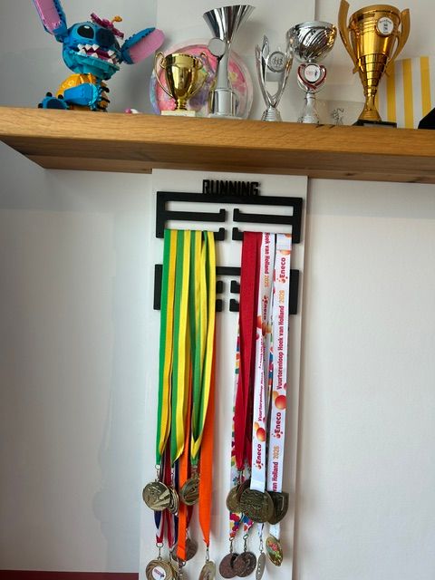 Running medaillerek met medailles onder een plank met sportbekers